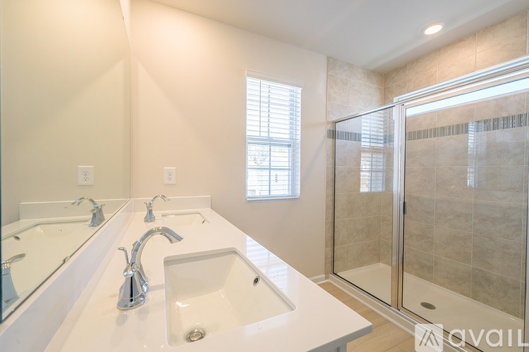 A bathroom with a large mirror, two sinks, and a walk-in shower.