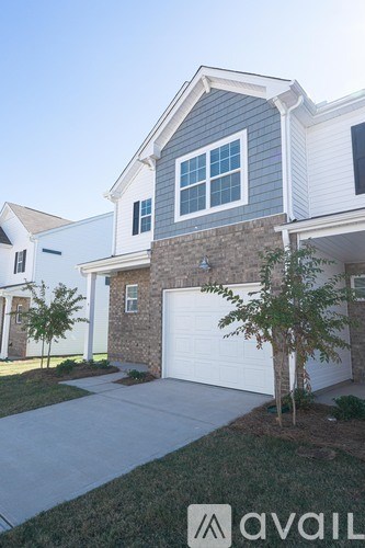 A house with a garage and a tree in front.