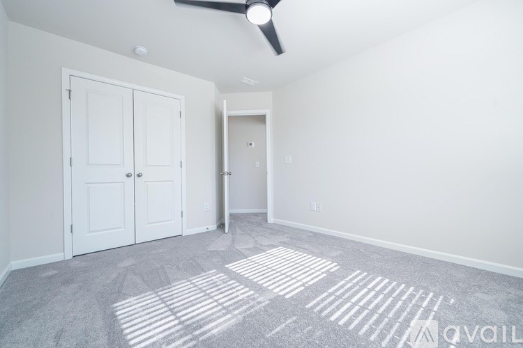 A room with a carpeted floor and a ceiling fan.