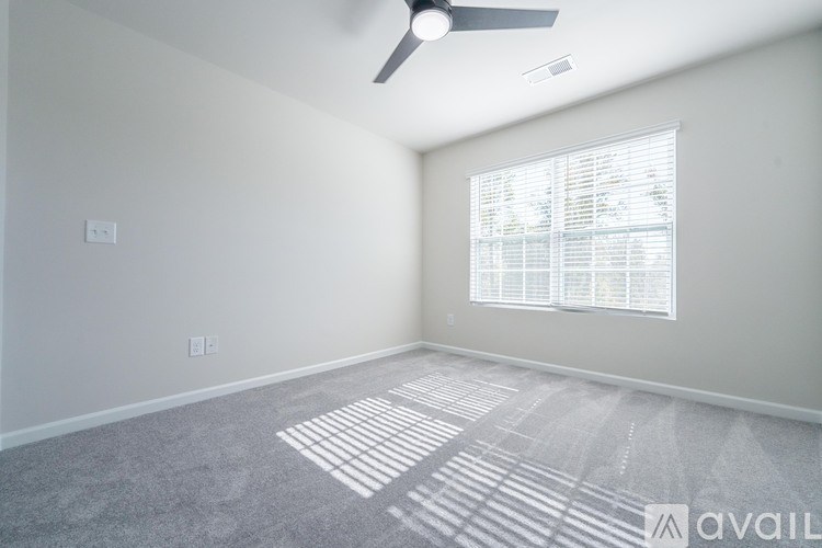 A room with a fan, window, and carpet.