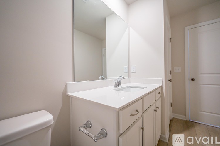 A white bathroom with a sink, mirror, and toilet.