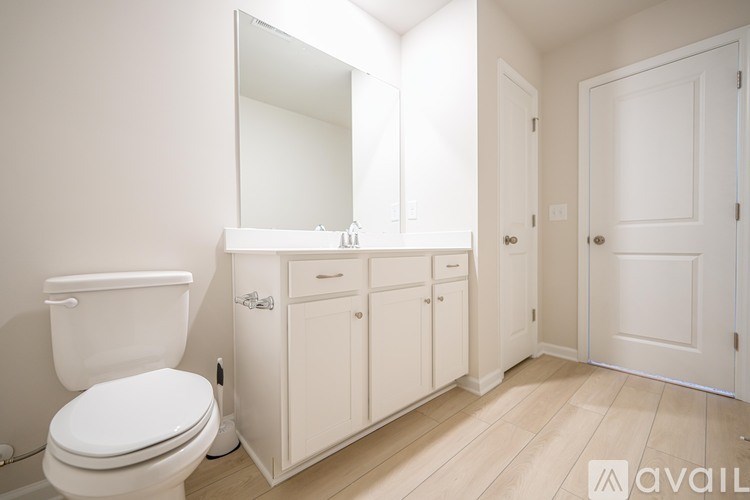 A white toilet sits next to a white cabinet with a mirror above it.