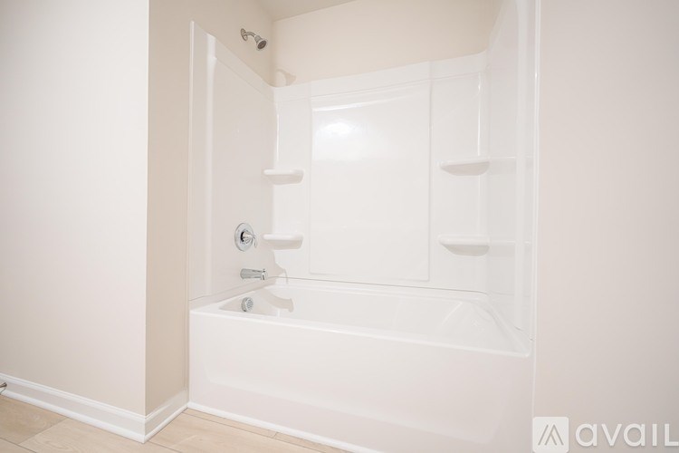 A white bathtub with a shower head and faucet.