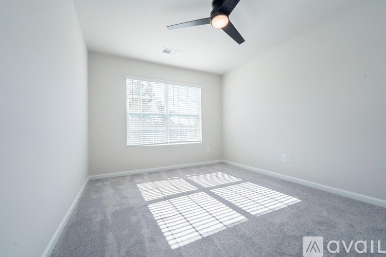 A room with a ceiling fan and a window with blinds.