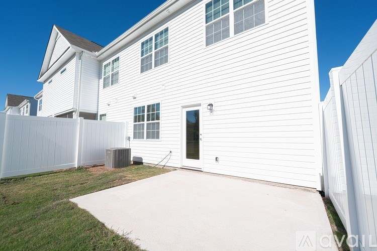 A white house with a black door and a white fence.