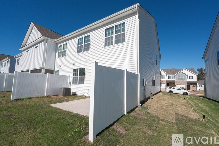 A white house with a brown roof and a white fence.