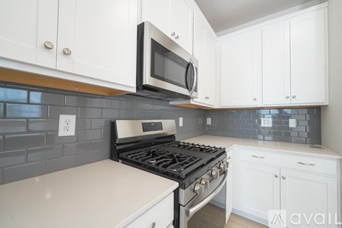 A kitchen with white cabinets and a black stove top oven.