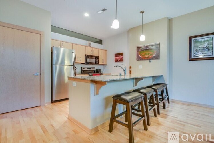 A kitchen with a refrigerator, stove, and bar stools.