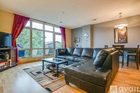 A living room with a black leather couch and a coffee table.