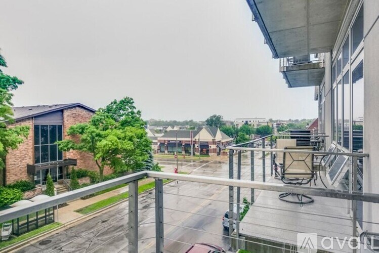 A rainy day view from a balcony overlooking a parking lot.