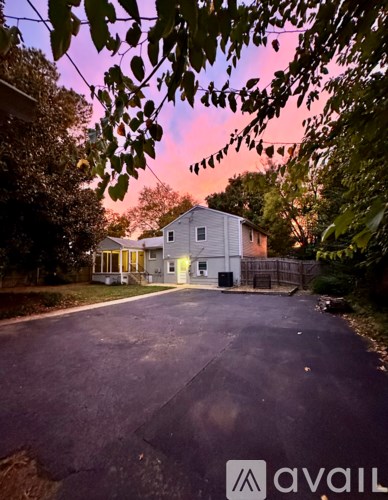 A house with a driveway and trees in the foreground.