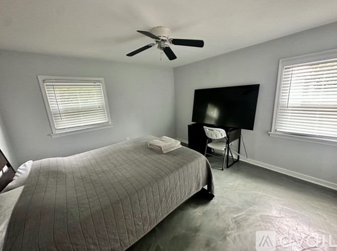 A bedroom with a bed, a chair, and a ceiling fan.