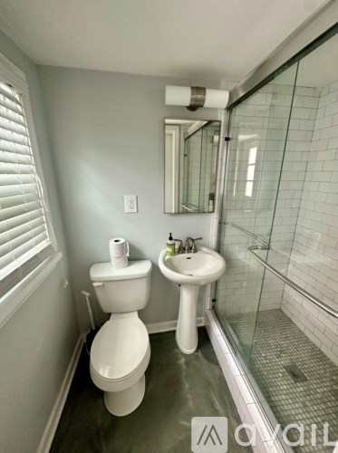 A white toilet sits next to a white sink in a bathroom.
