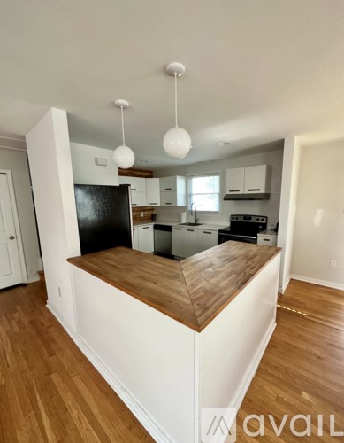 A kitchen with white cabinets and a wooden countertop.