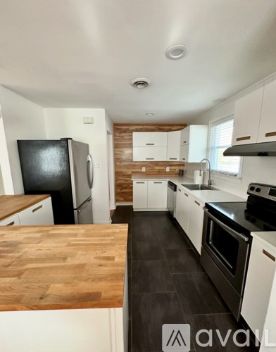 A kitchen with a wooden counter top and black appliances.