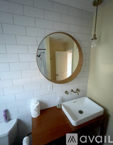 A bathroom with a white sink and a round mirror.