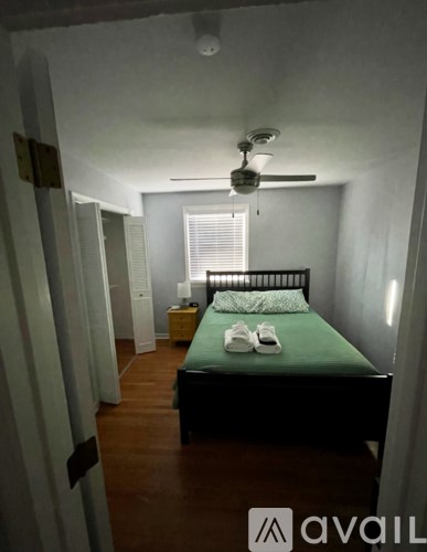 A bedroom with a bed, a ceiling fan, and a window with blinds.