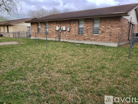 A brick house with a fence and a grassy yard.