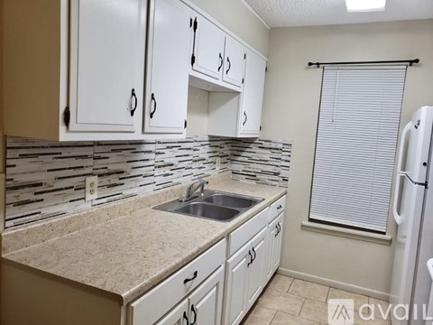 A kitchen with white cabinets and a beige countertop.