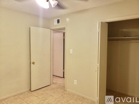 A room with a white door and a ceiling fan.
