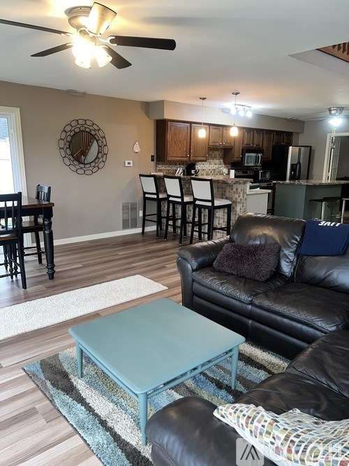A living room with a black leather couch and a blue coffee table.