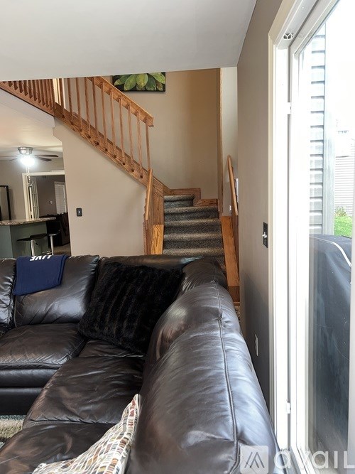 A black leather couch with a blue pillow on it.