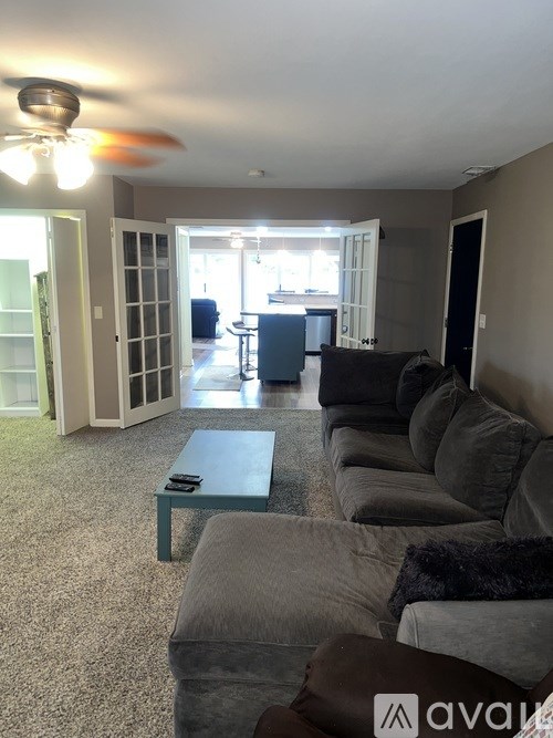 A living room with a grey couch and a ceiling fan.