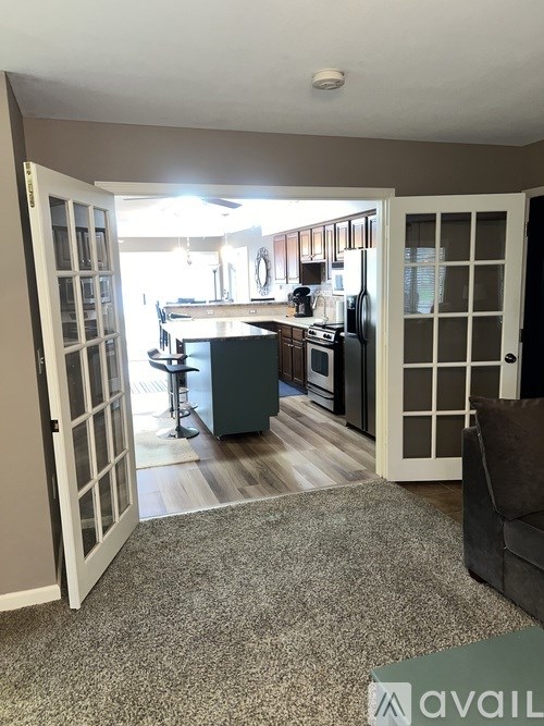 A kitchen area with a bar stool and a fridge.