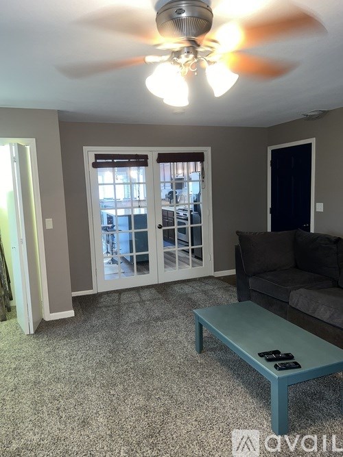 A living room with a ceiling fan and a grey couch.