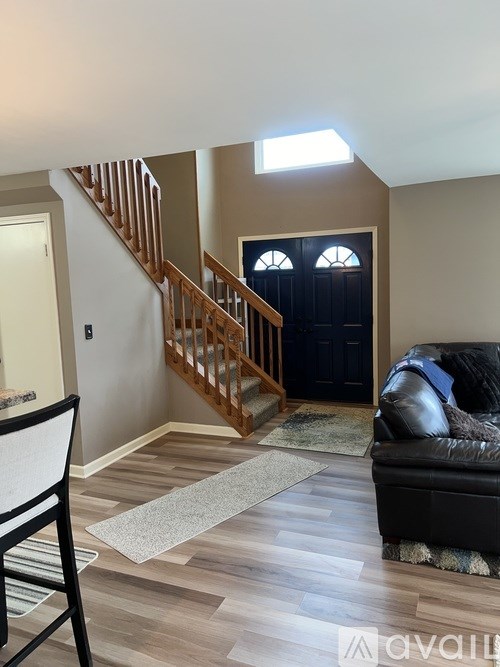 A living room with a black couch and a wooden staircase.