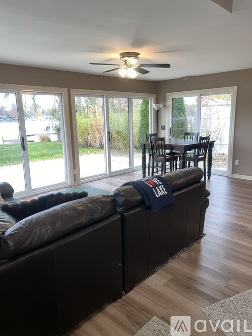 A living room with a couch, a fan, and a dining table.