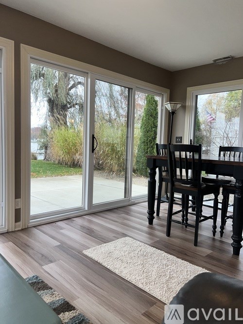 A dining room with a table and chairs and a view of the outside through the sliding glass doors.