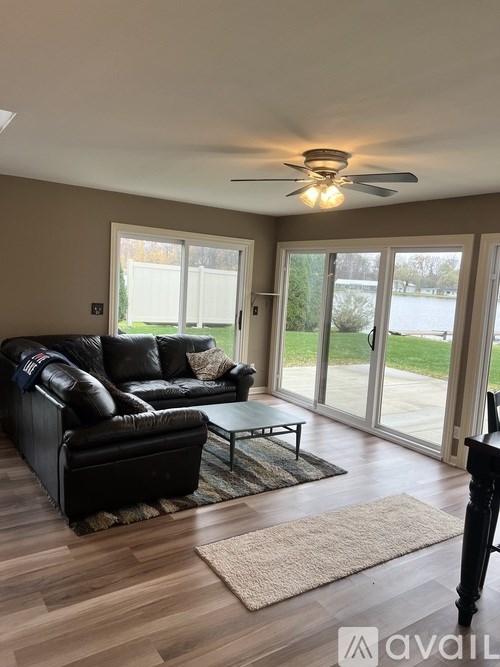 A living room with a black leather couch and a ceiling fan.
