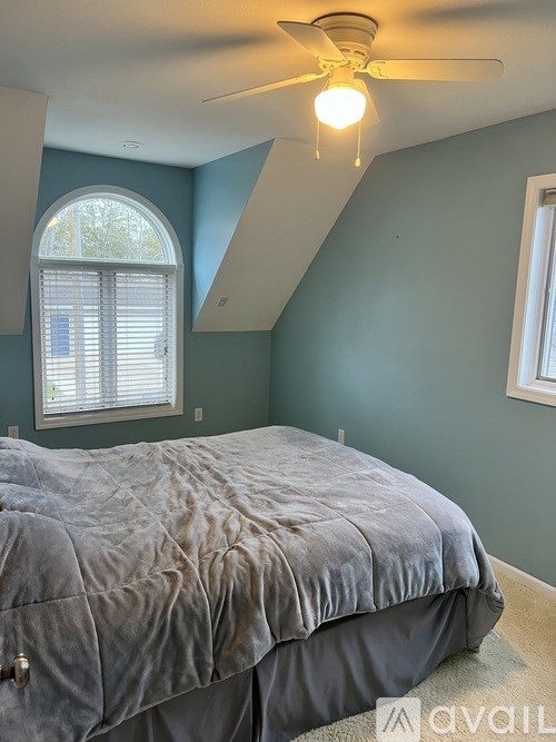 A bedroom with a bed and a ceiling fan.