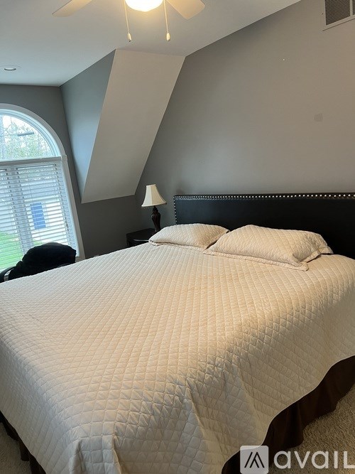 A bed with a white comforter and a black headboard.