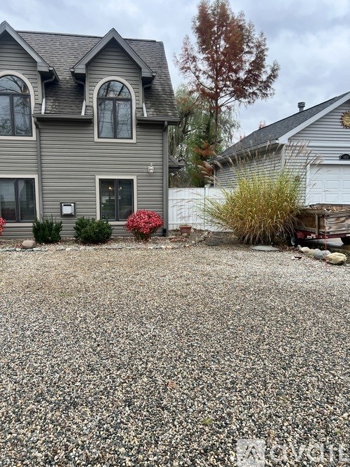 A grey house with a gravel driveway in front.