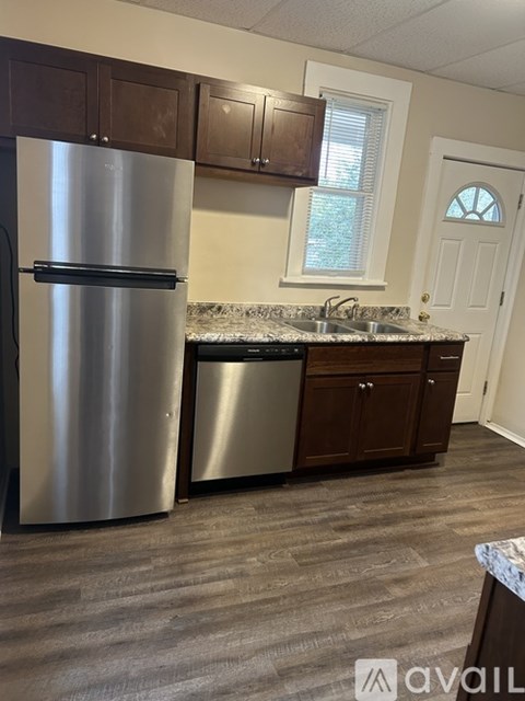 A kitchen with a stainless steel refrigerator and wooden cabinets.