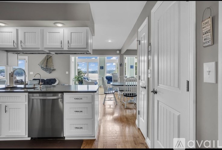A modern kitchen with white cabinets and a wooden floor.