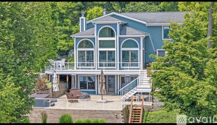 A house with a blue exterior and a deck with chairs and an umbrella.