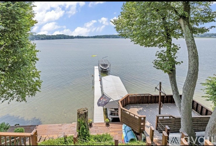 A view of a lake from a deck with a canopy and a boat.