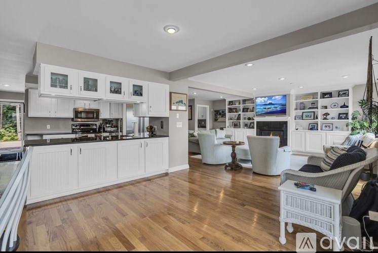 A modern kitchen with white cabinets and a wooden floor.
