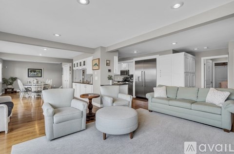 A spacious living room with a grey sofa and white furniture.