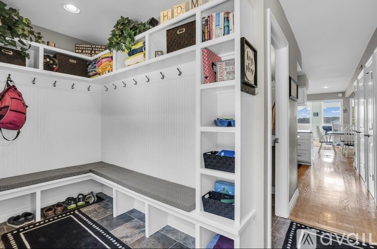 A white shelving unit with a red backpack hanging on the wall.