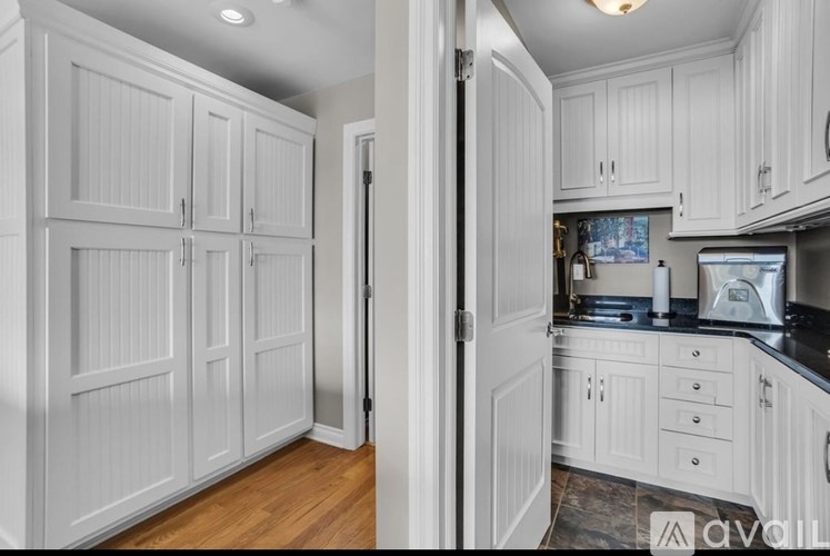 A kitchen with white cabinets and a black countertop.