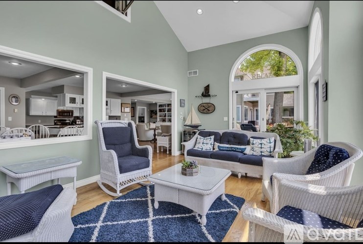 A living room with white furniture and a blue rug.