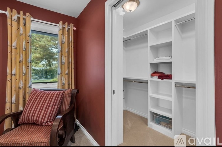 A room with a red chair and a white closet.