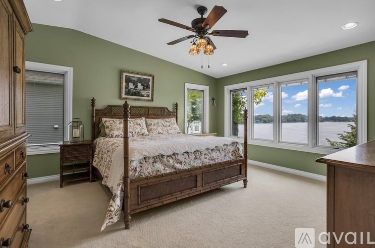 A bedroom with a large bed, wooden furniture, and a ceiling fan.