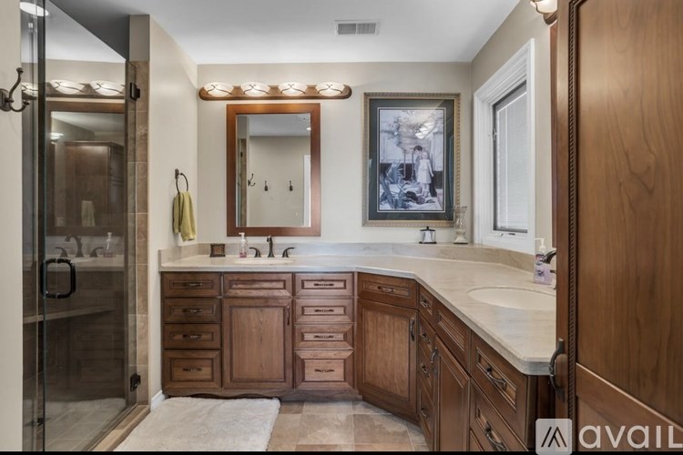 A bathroom with a wooden vanity and a glass shower stall.
