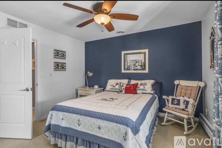 A bedroom with a bed, chair, and ceiling fan.