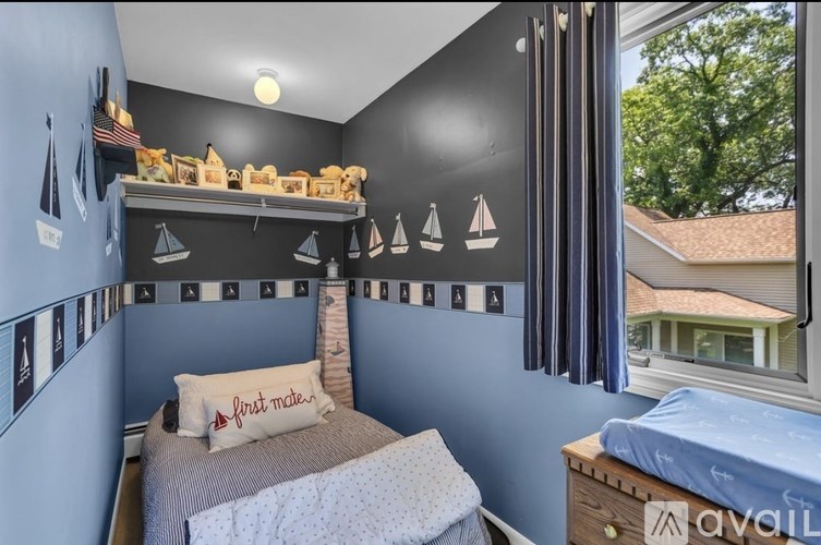 A bedroom with a bed, a dresser, and a window with curtains.